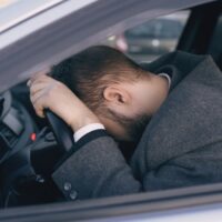 Young bearded business man sitting in car very upset and stressed after hard failure and moving in traffic jam