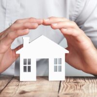 Protecting Hands Over House - Home Security And Protection Concept Protecting Hands Over House - Home Security And Protection Concept