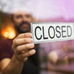 owner puts closed sign at bar or restaurant window