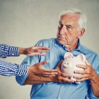 senior man holding piggy bank suspicious protecting savings