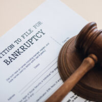 High angle view of gavel on document with petition to file for bankruptcy lettering isolated on beige