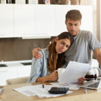 Negative human emotions. Financial problems. Portrait of unhappy young couple having looking worried while reading notification informing them about eviction from apartment because of unpaid bills Negative human emotions. Financial problems. Portrait of unhappy young couple having looking worried while reading notification informing them about eviction from apartment because of unpaid bills