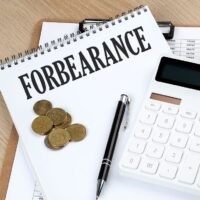 FORBEARANCE text on notebook with chart and calculator and coins, business concept FORBEARANCE text on notebook with chart and calculator and coins, business concept
