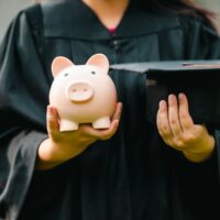 graduates holding piggy banks saving concept