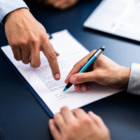 Pointing The Finger In Front Of A Person Signing The Document Pointing The Finger In Front Of A Person Signing The Document
