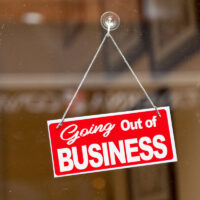 Red sign hanging at the glass door of a shop saying: "Going out of business".