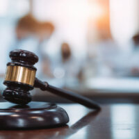 Gavel slamming on table in front of a blurred group of medical staff working together, a courtroom concept