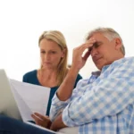 Couple, couch and document with laptop and stress, finances or taxes for debt in lounge. Paperwork, man and female person or online for mortgage, upset and budget for inflation or bankruptcy in home