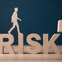 A person balancing on the word risk with a block being added A person balancing on the word risk with a block being added